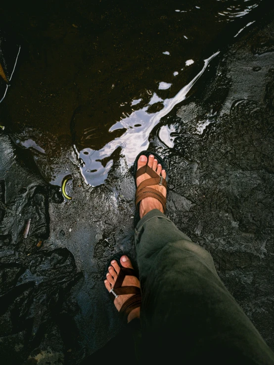 a person standing on a rock next to a body of water, dirty floor, sandals, intricate and wet oil paint, instagram post