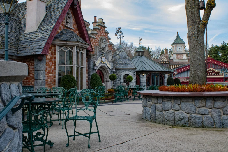 a patio area with tables and chairs and a clock tower in the background, a photo, inspired by Serafino De Tivoli, pexels contest winner, art nouveau, background is disneyland castle, fantasy village, wintry rumpelstiltskin, panoramic shot