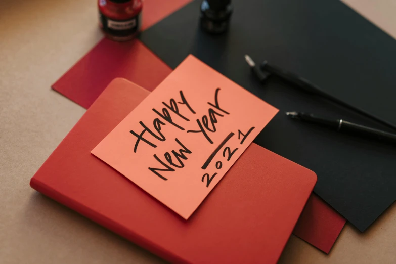 a note with the words happy new year written on it, trending on pexels, private press, red and black color palette, profile image, inks, cardboard