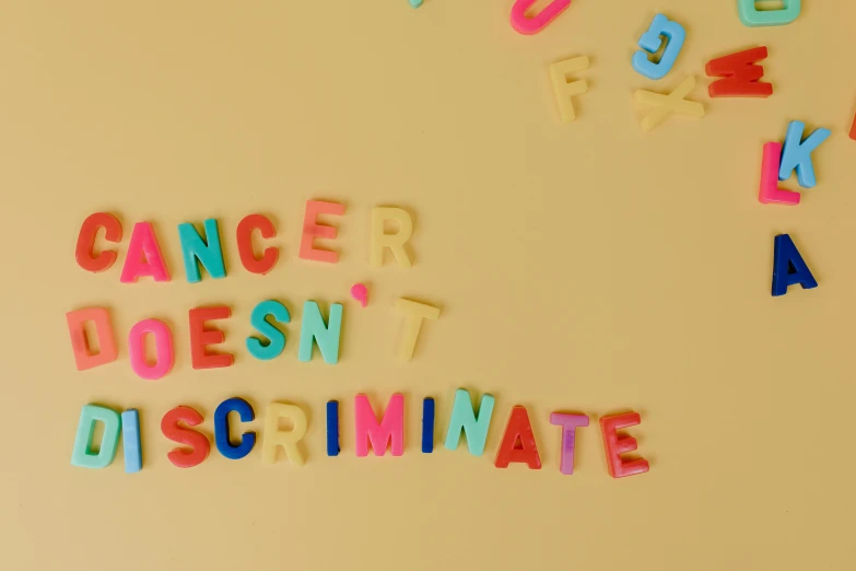 a refrigerator with magnets that say cancer doesn't discriminate, by Liza Donnelly, trending on pexels, feminist art, neon pastel, letter s, human character, skin color