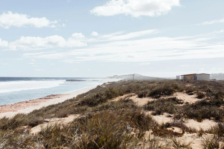 a man riding a surfboard on top of a sandy beach, by Lee Loughridge, unsplash, happening, an australian summer landscape, a road leading to the lighthouse, hollister ranch, view from a distance