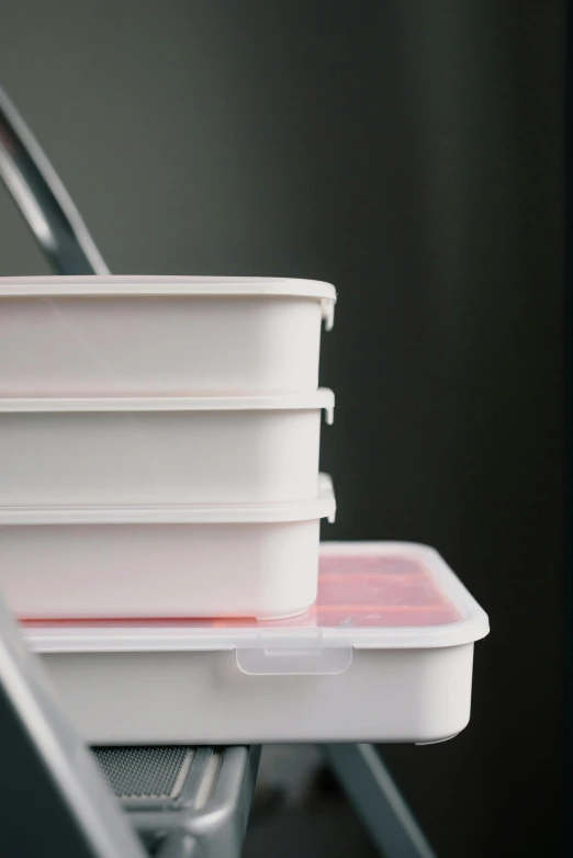 a stack of plastic containers sitting on top of a table, pexels, white mechanical details, stew, white box, low light