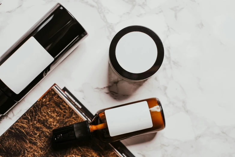 a couple of bottles sitting on top of a table, pexels contest winner, minimalism, skincare, ink and paper, brown hair in a ponytail, close-up product photo