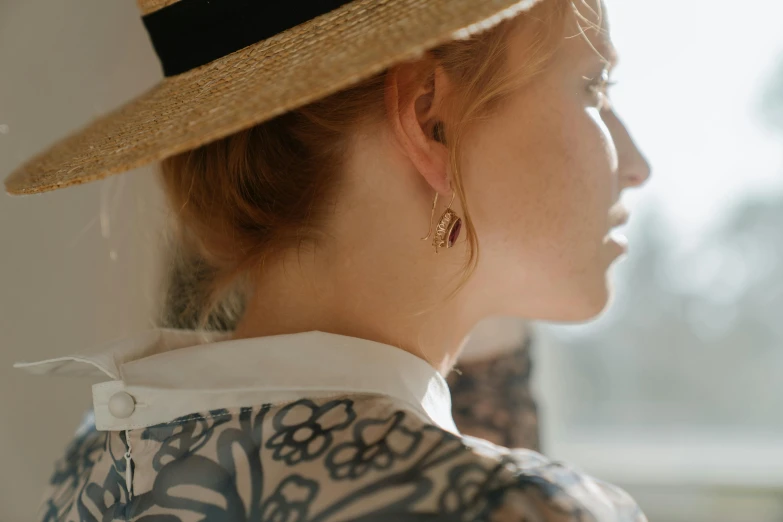 a close up of a person wearing a hat, by Emma Andijewska, trending on pexels, renaissance, an earring, delicate patterned, summer light, facing away