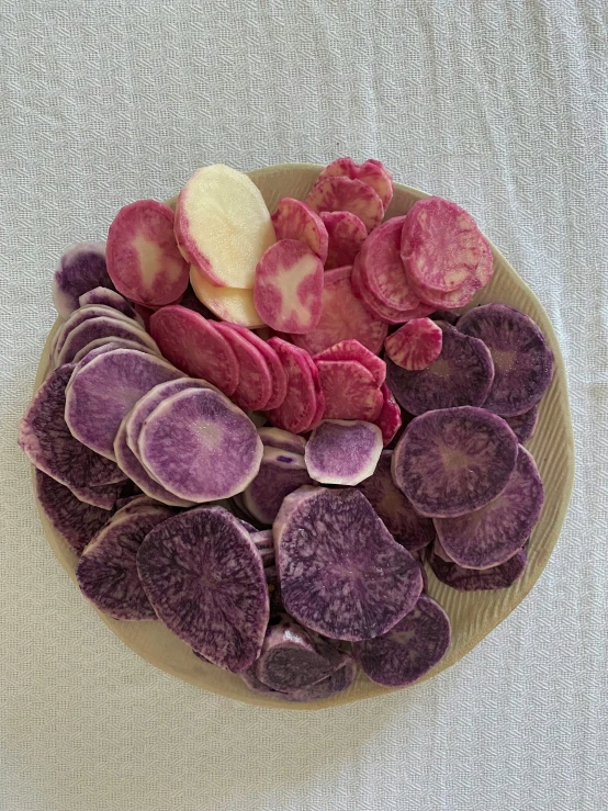 a plate of purple and white potatoes on a table, by Jessie Algie, process art, red and purple coloring, chips, various sizes, velvet