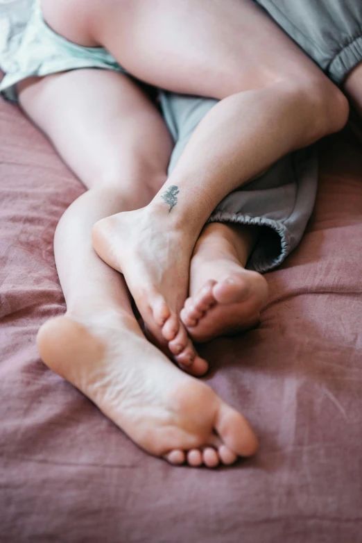 a close up of a person laying on a bed, a tattoo, legs intertwined, hugging each other, beds, maternal