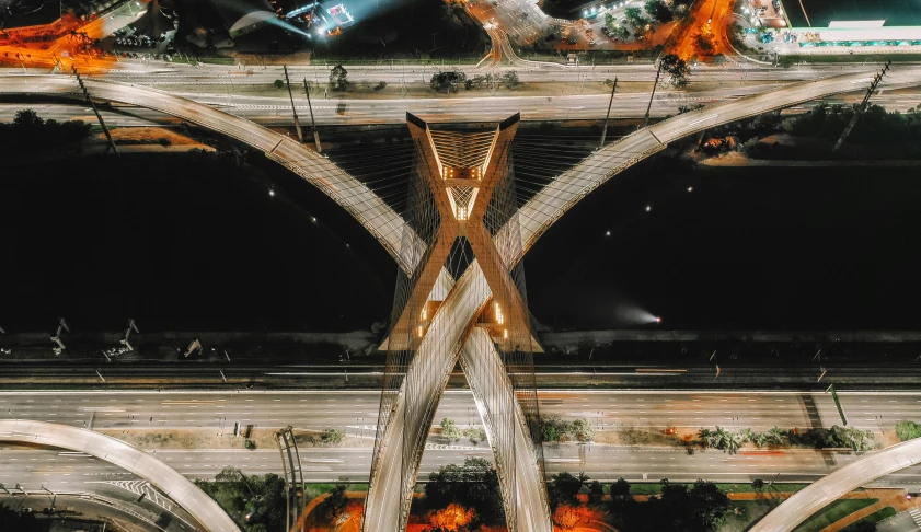 an aerial view of a highway intersection at night, by Alejandro Obregón, pexels contest winner, elegant bridges between towers, professional iphone photo, symmetrical artwork, massive arch