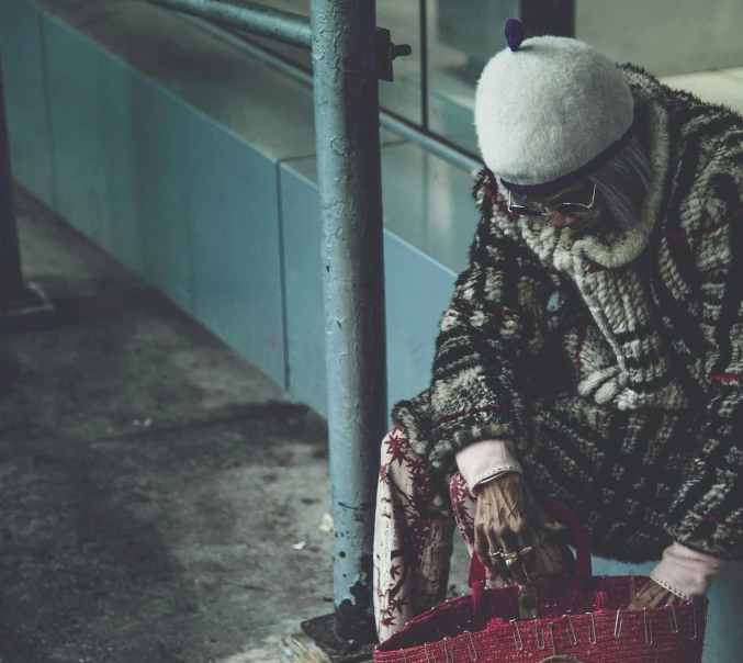 a man that is sitting down with a bag, a picture, inspired by Elsa Bleda, pexels contest winner, hurufiyya, an old lady with red skin, cyberpunk homeless, patterned clothing, asian woman