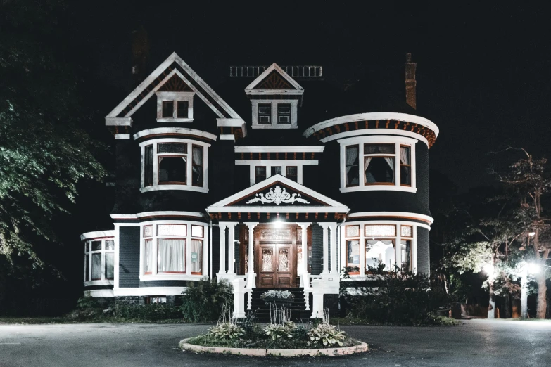 a black and white house lit up at night, pexels contest winner, art nouveau, new england architecture, background image, victorian goth, reddish exterior lighting