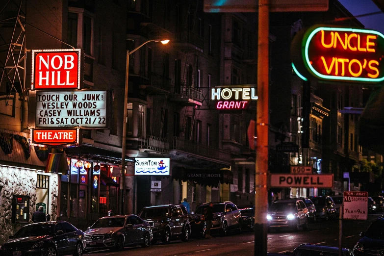 a street filled with lots of traffic next to tall buildings, by Matt Stewart, pexels contest winner, dimly lit dive bar, motel, old signs, san francisco