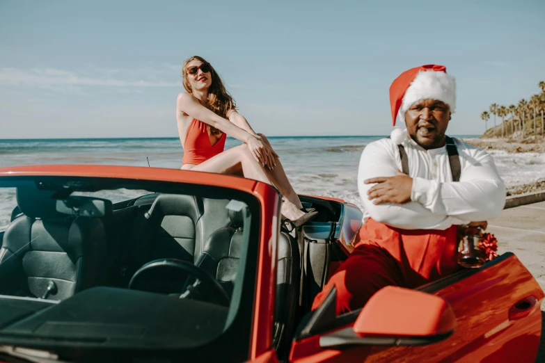 a man sitting on top of a red car next to a woman, holiday vibe, dr zeus, santa clause, coast