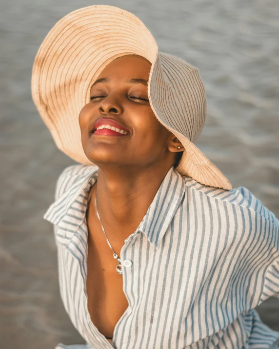 a close up of a person wearing a hat, posing on the beach, queer woman, wearing a linen shirt, smiling down from above