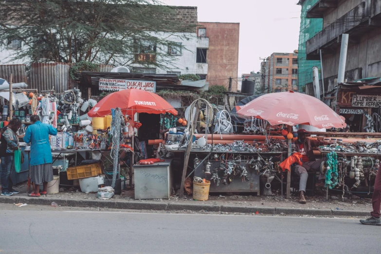 a group of people standing on the side of a road, by Daniel Lieske, trending on unsplash, temporary art, fish market stalls, made from mechanical parts, unmistakably kenyan, wet streets