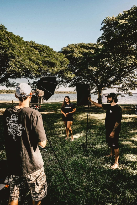 a group of people standing on top of a lush green field, a portrait, by Robbie Trevino, unsplash, visual art, surf photography, behind the scenes photo, giving an interview, filmic lighting