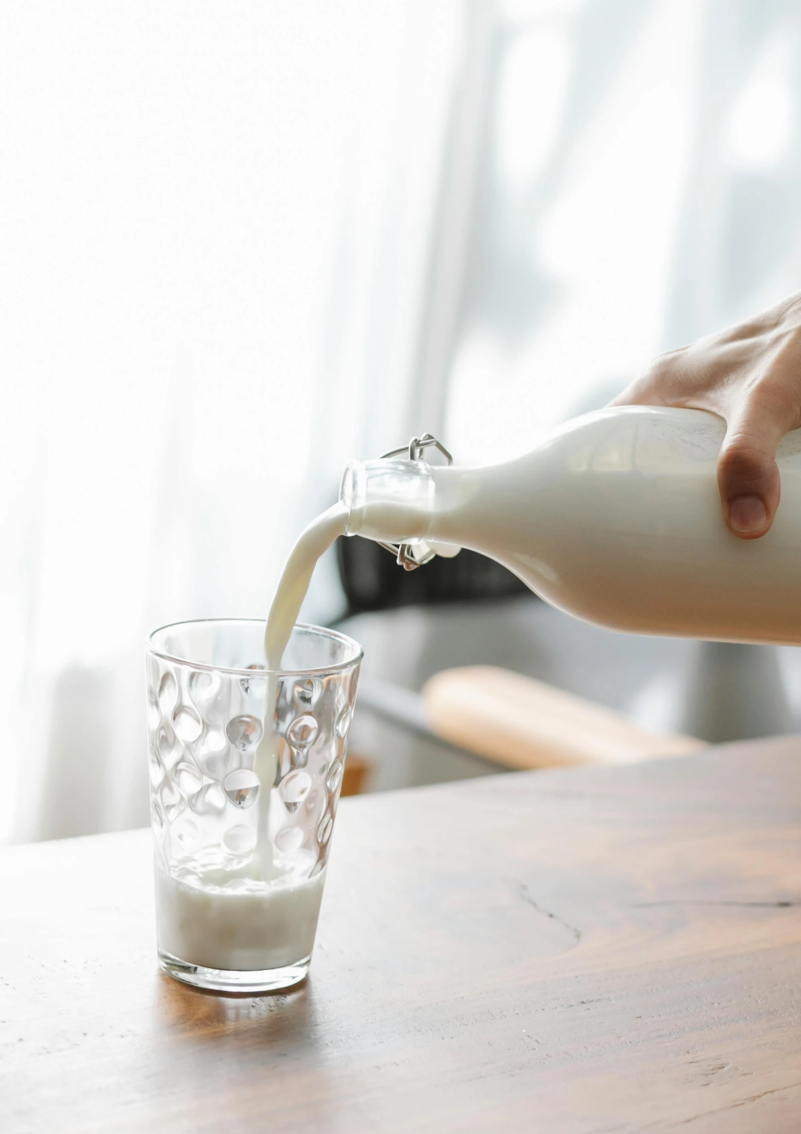 a person pouring milk into a glass on a table, no - text no - logo, soymilk, 4l, large tall