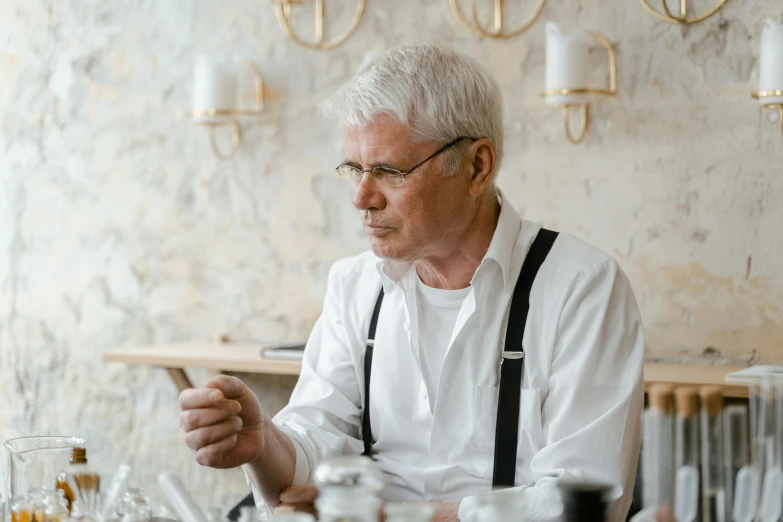 a man sitting at a table using a cell phone, a portrait, by Peter Churcher, pexels contest winner, white waist apron and undershirt, silver haired, silver small glasses, slightly minimal