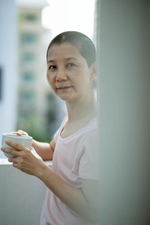 a woman standing in front of a window holding a cup, inspired by Cui Bai, close - up photograph, 4 5 yo, breakfast, profile image