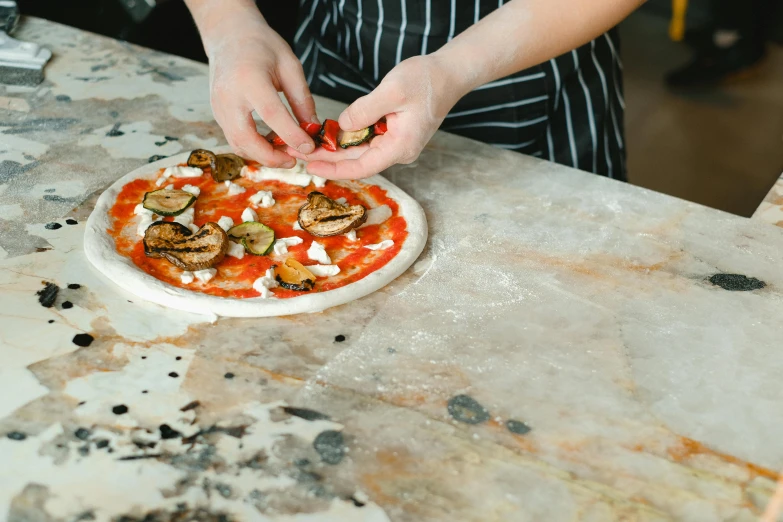 a person putting toppings on a pizza on a table, by Julia Pishtar, pexels contest winner, carved in marble, square, snail, 15081959 21121991 01012000 4k