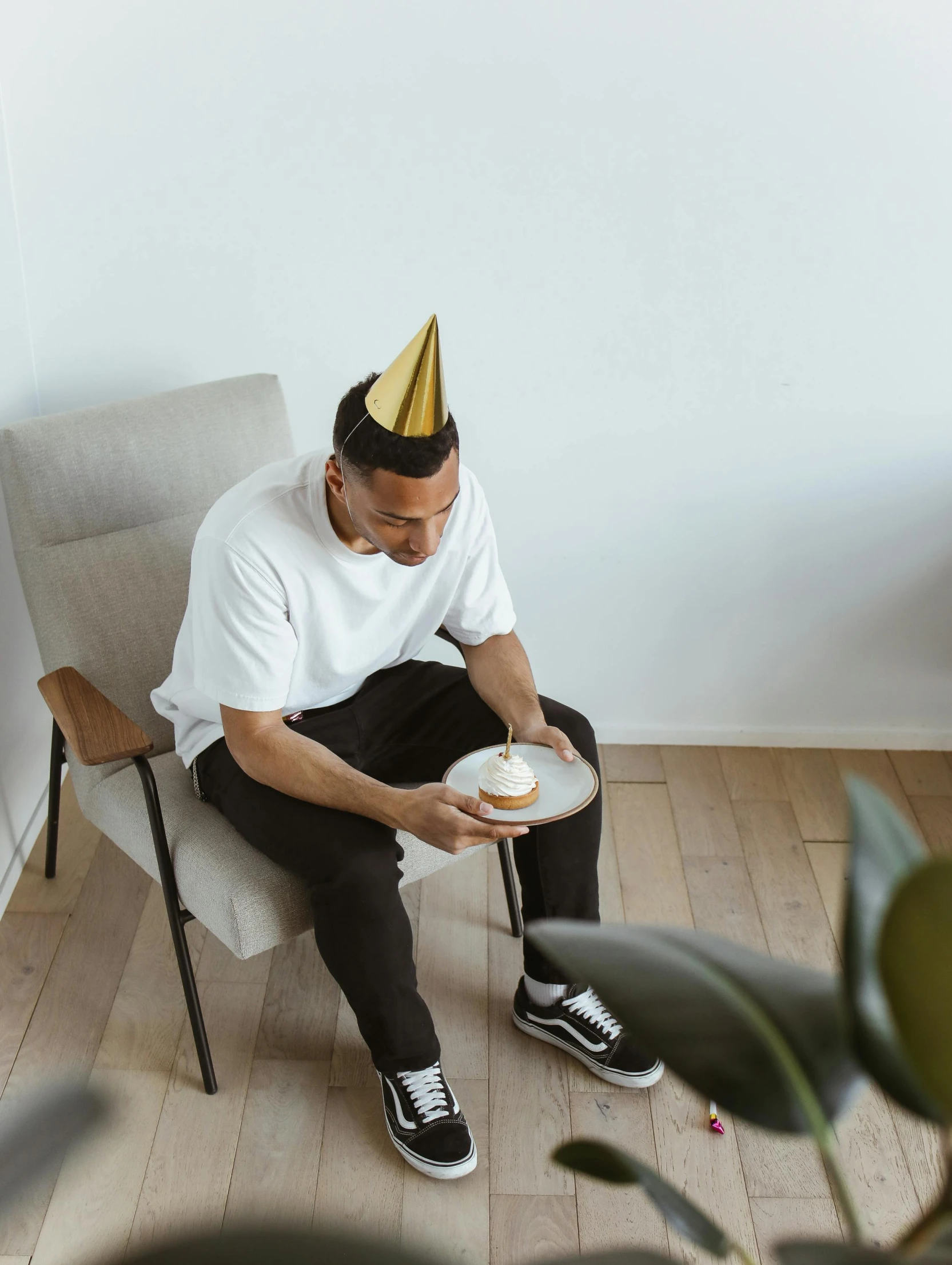 a man sitting in a chair wearing a party hat, trending on unsplash, happening, birthday cake on the ground, very minimalistic, gif, lean man with light tan skin