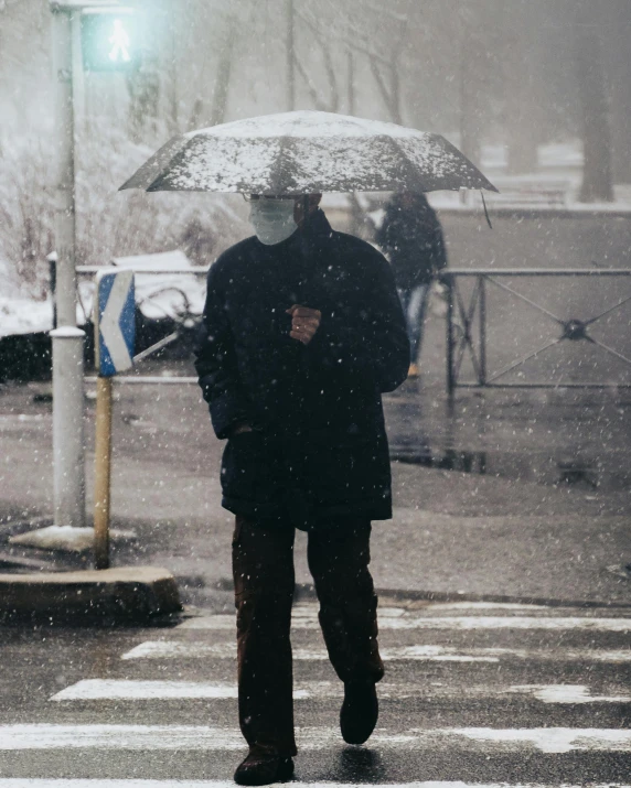 a man walking across a street holding an umbrella, by Lucia Peka, trending on unsplash, covered in salt, lgbt, face covered, dressed in a gray