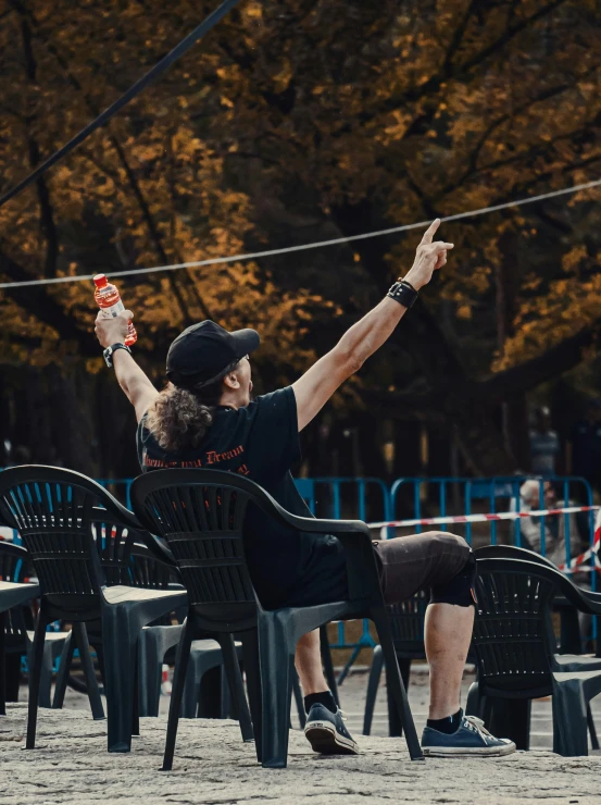 a man flying a kite on top of a sandy beach, by Adam Marczyński, pexels contest winner, happening, drinking at the bar, marathon race, sitting on a metal throne, at a park