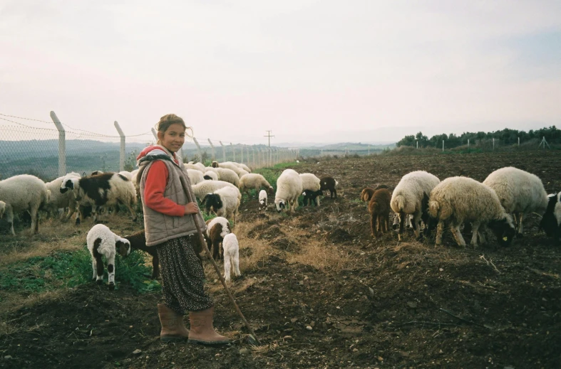 a woman standing in front of a herd of sheep, by Elsa Bleda, gardening, 40 years old women, mediterranean, cinematic full shot