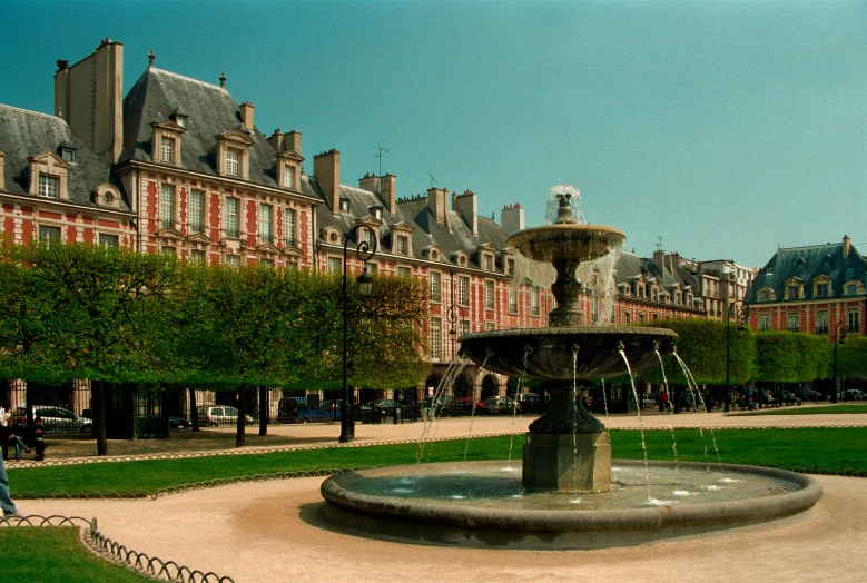 a fountain sitting in the middle of a lush green park, inspired by Pierre Toutain-Dorbec, pexels contest winner, town square, rennes - le - chateau, 2000s photo, square