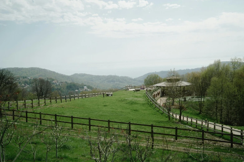 a large grassy field with a wooden fence, inspired by Mirabello Cavalori, unsplash, renaissance, in the hillside, green terrace, of augean stables, conde nast traveler photo