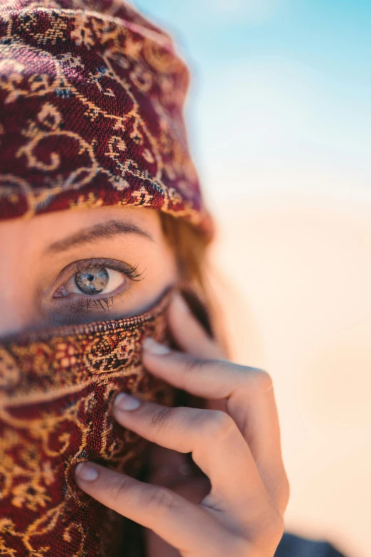 a woman with a scarf covering her face, trending on unsplash, renaissance, arabian nights inspired, in the desert, super detailed eyes, with blue eyes