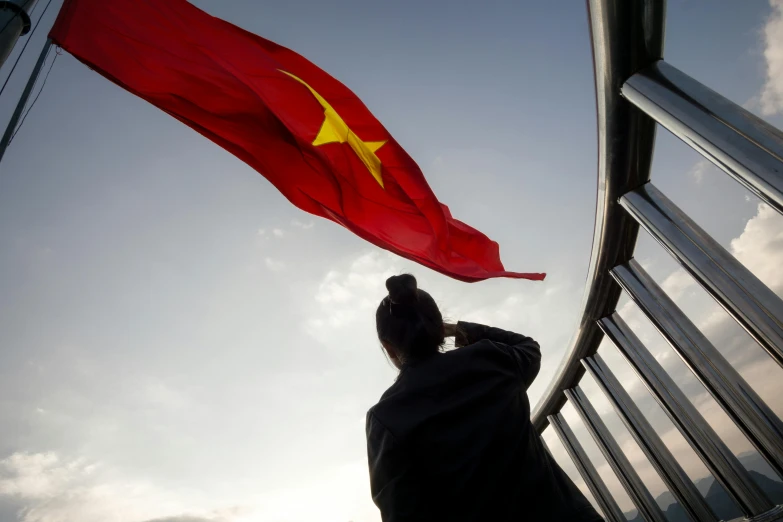 a woman looking up at a vietnamese flag, by Julia Pishtar, happening, square, ap, high quality image, overlooking