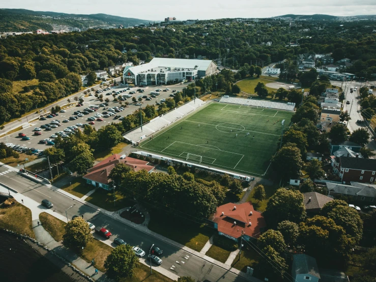 an aerial view of a soccer field surrounded by trees, quebec, grass field surrounding the city, 🚿🗝📝, local gym