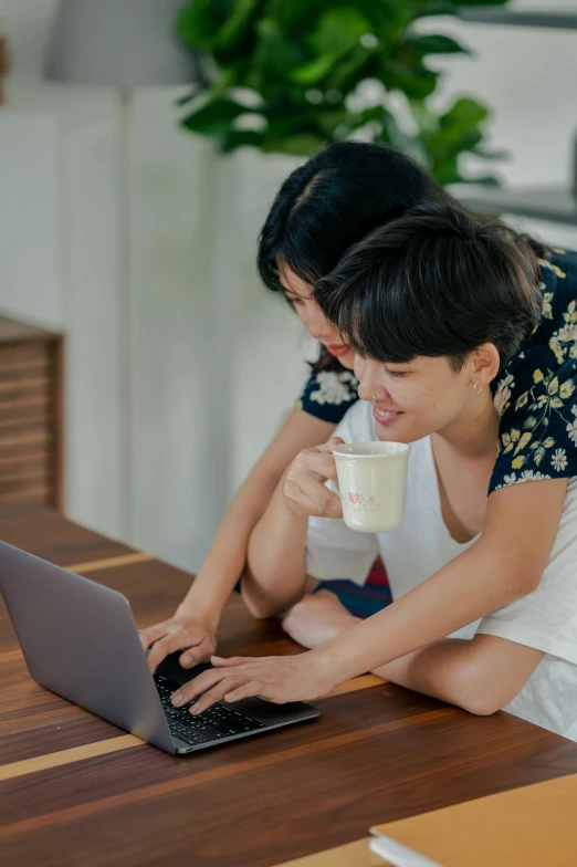 a couple of women sitting at a table with a laptop, pexels contest winner, happening, asian male, milk, home office, lesbian