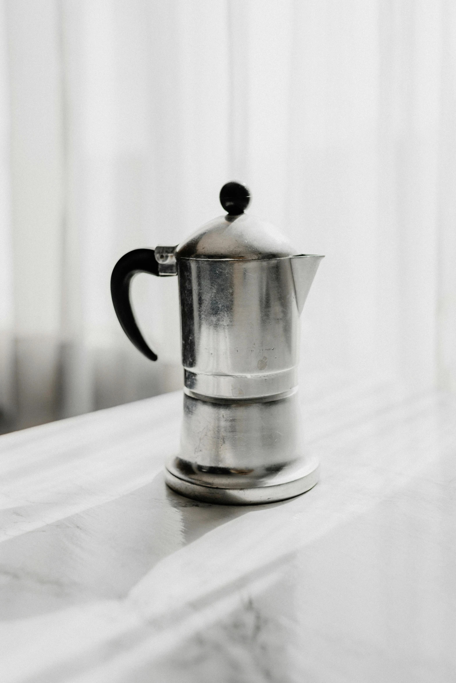 a silver coffee pot sitting on top of a counter, unsplash, italian, extremely grainy, on a pale background, 5 k