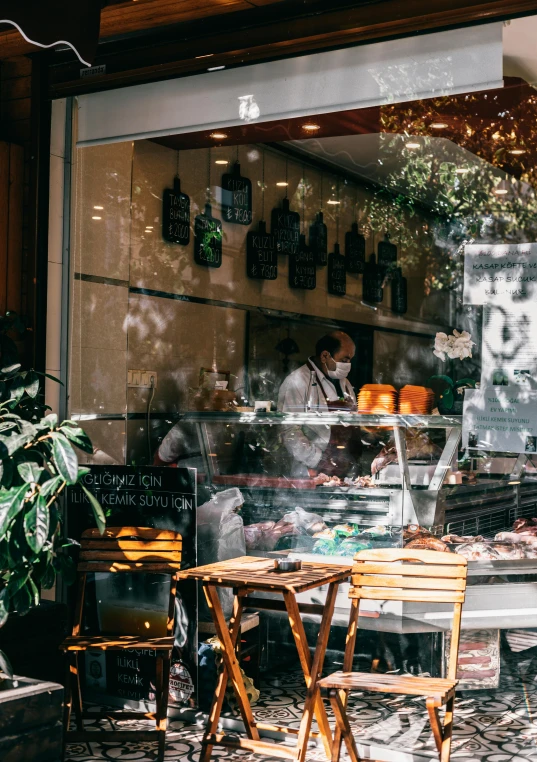 a man sitting at a table in front of a bakery, pexels contest winner, renaissance, modern lush condo as shopfront, butcher, thumbnail, window