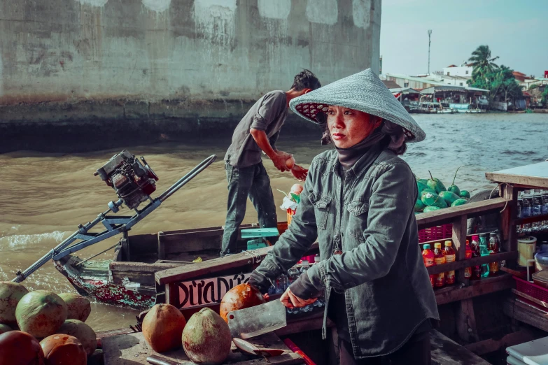 a woman standing on top of a boat filled with fruit, inspired by Steve McCurry, pexels contest winner, emma watson vietnam door gunner, square, thumbnail, pith helmet