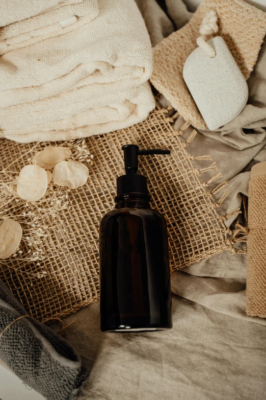 a bottle of lotion sitting on top of a bed, by Andries Stock, pexels contest winner, renaissance, burlap, black resin, thumbnail, soap