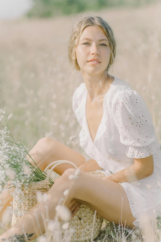 a woman sitting in a field of tall grass, inspired by Beatrice Huntington, trending on pexels, white outfit, sydney sweeney, holding flowers, gif