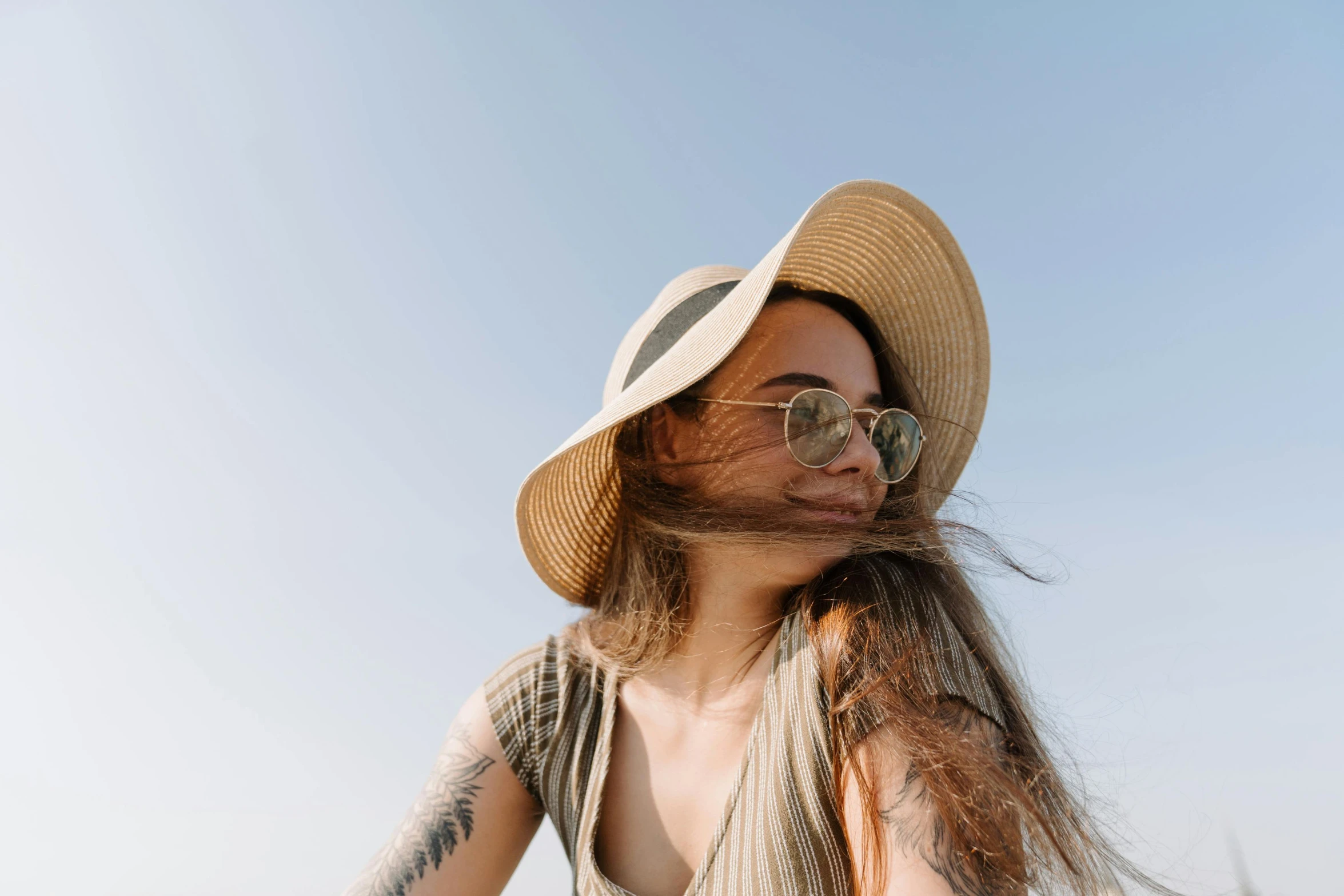 a woman with her hair blowing in the wind, trending on pexels, wearing sunglasses and a hat, 1 2 9 7, long chin, ad image