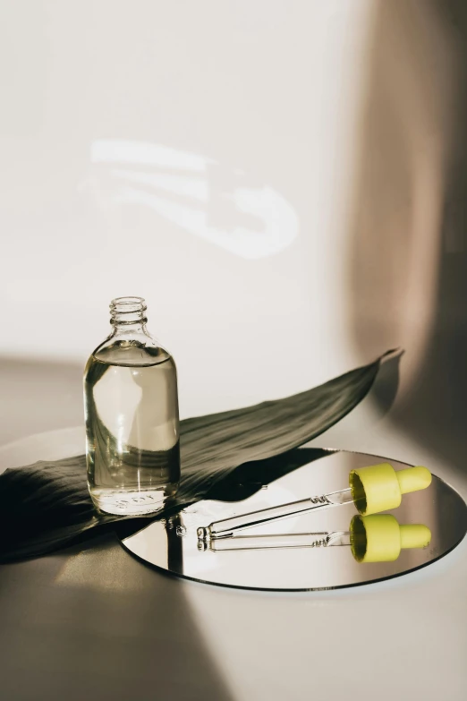 a bottle of liquid sitting on top of a table, trending on pexels, minimalism, magnolia leaves and stems, synthetic bio skin, mirror dripping droplet, thumbnail