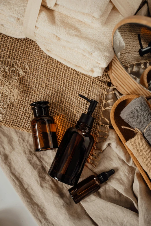 a basket filled with personal care items sitting on top of a bed, a still life, by Andries Stock, unsplash, alchemist bottles, burlap, brown resin, detailed product image