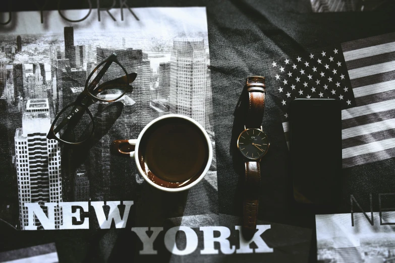 a cup of coffee sitting on top of a table, watching new york, exquisite black accessories, new york, black and brown