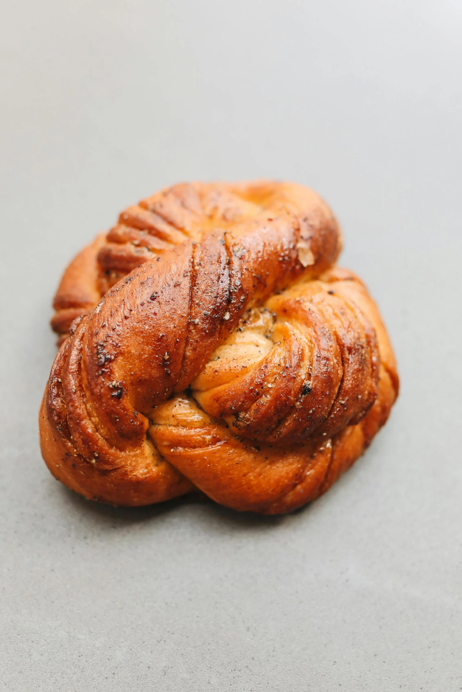 a close up of a pastry on a table, orange braided hair, luscious with sesame seeds, nordic crown, solid grey