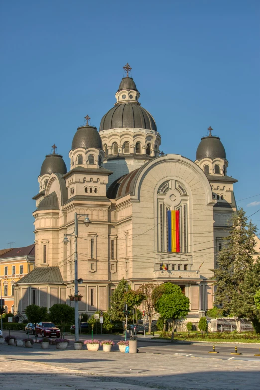 a large building with a clock tower in front of it, inspired by Ștefan Luchian, romanesque, church cathedral, lgbtq, traditional romanian clothing, with great domes and arches