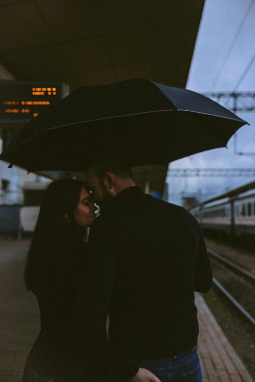 a man and a woman standing under an umbrella, unsplash contest winner, romanticism, train station, black, profile pic, holding each other