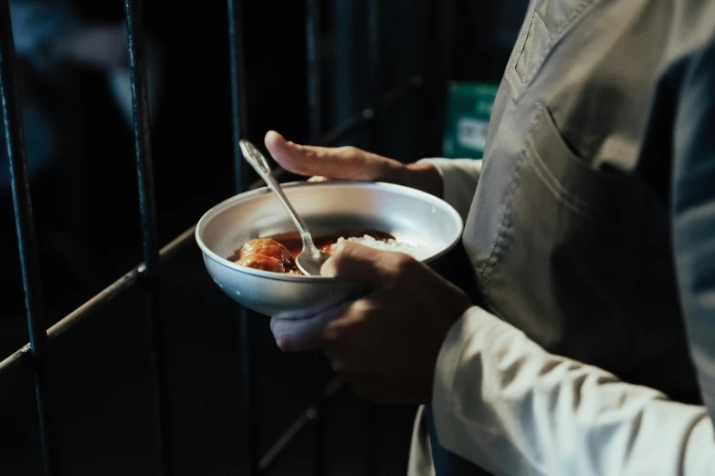 a close up of a person holding a bowl of food, pexels contest winner, hurufiyya, in prison, serving suggestion, end of the day, cast