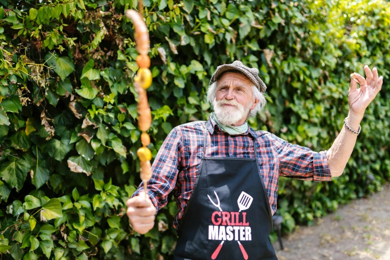 a man standing in front of a hedge holding a stick, inspired by Ernest Buckmaster, pexels contest winner, arts and crafts movement, grill, old man doing with mask, dressed as a pastry chef, ripped clothes holding whip