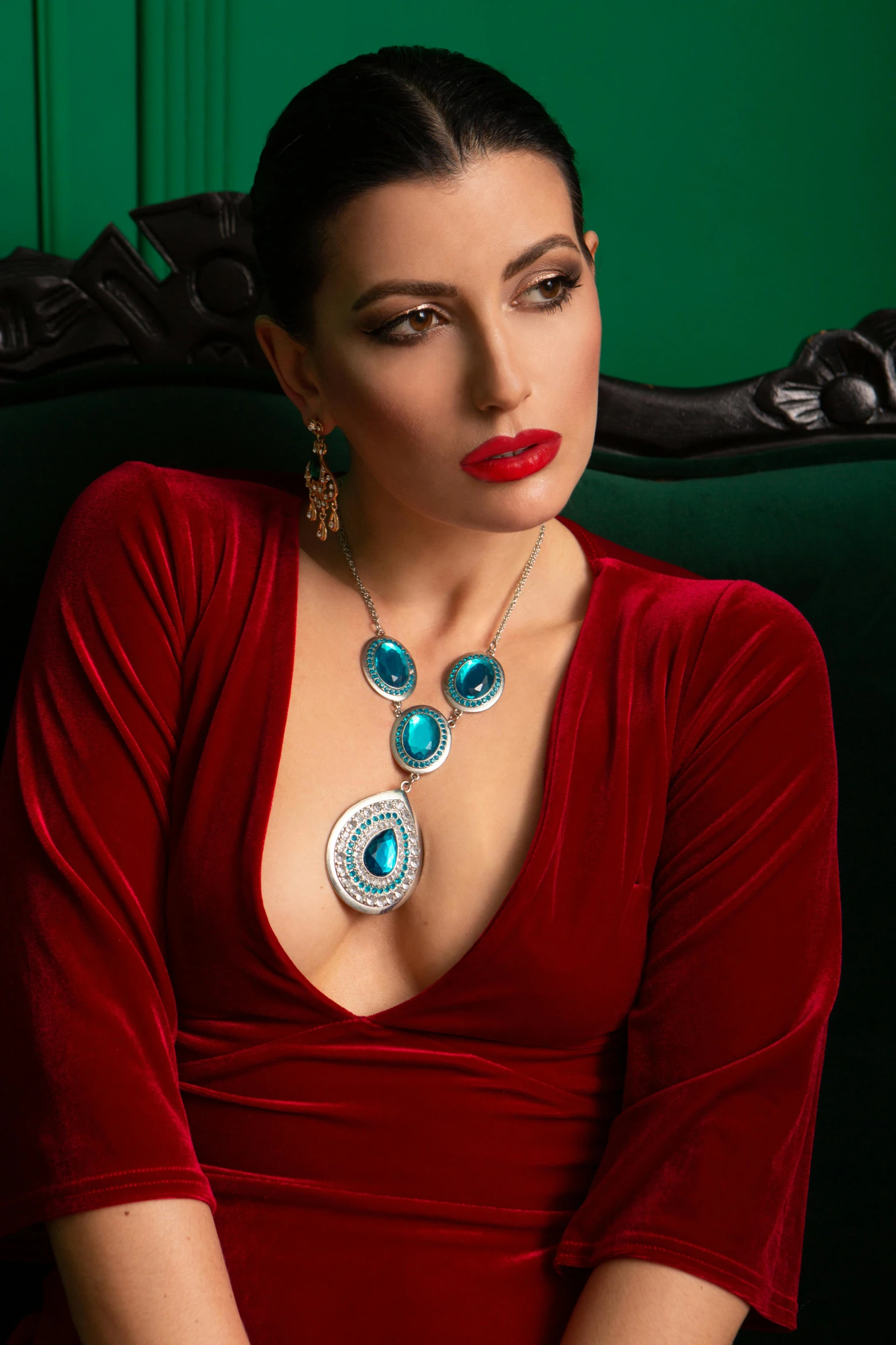 a woman in a red dress sitting on a couch, inspired by Ramon Pichot, renaissance, turquoise jewelry, necklace on display, teal silver red, embedded with gemstones