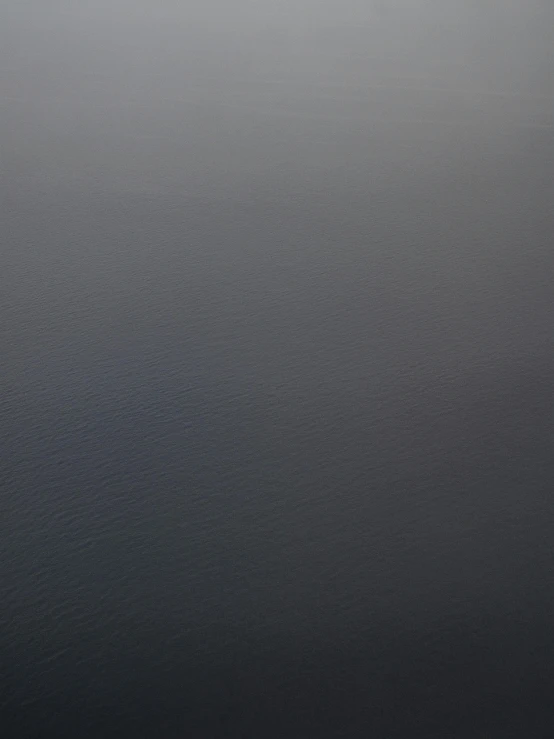 a boat floating on top of a body of water, an album cover, inspired by Andreas Gursky, unsplash, tonalism, in gunmetal grey, very realistic. fog, 144x144 canvas, view from above on seascape