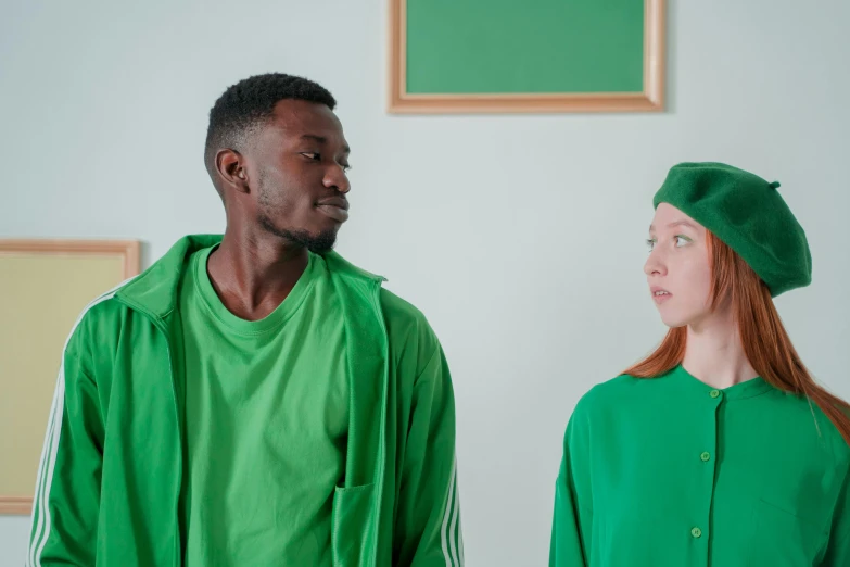 a man and a woman standing next to each other, trending on pexels, renaissance, green hood, wearing a school soccer uniform, dark people discussing, green colored skin