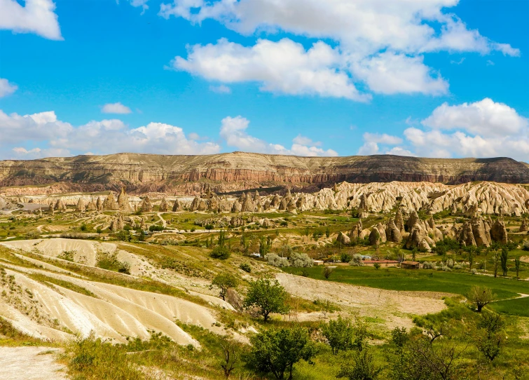 a dirt road running through a lush green valley, by Muggur, pexels contest winner, art nouveau, panorama of crooked ancient city, chiseled formations, beige, turkey